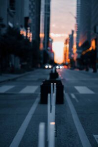 City street at sunset with blurred road dividers, warm light on tall buildings in background.